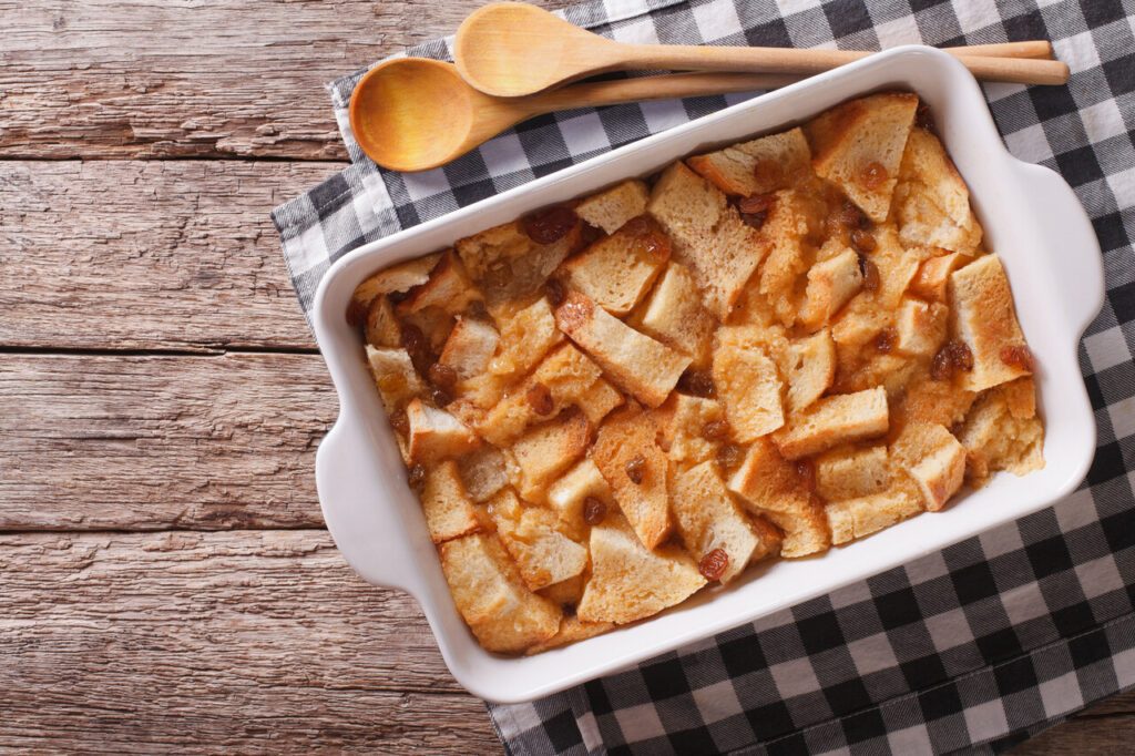 Fresh-baked English bread pudding with raisins in baking dish on the table. 