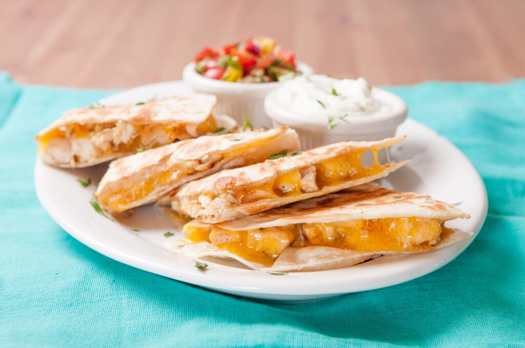 Mini chicken quesadillas using tortillas cut into fourths with cheese, chicken, and salsa