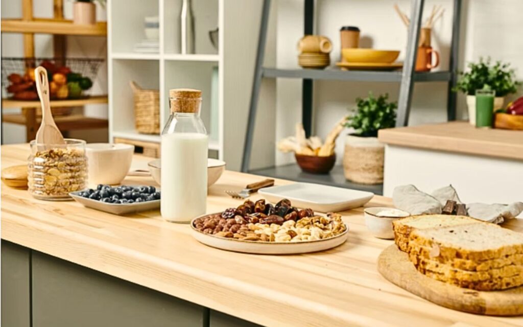 A well-stocked kitchen counter with everyday staples including eggs, pasta, bread, cheese, potatoes, frozen vegetables