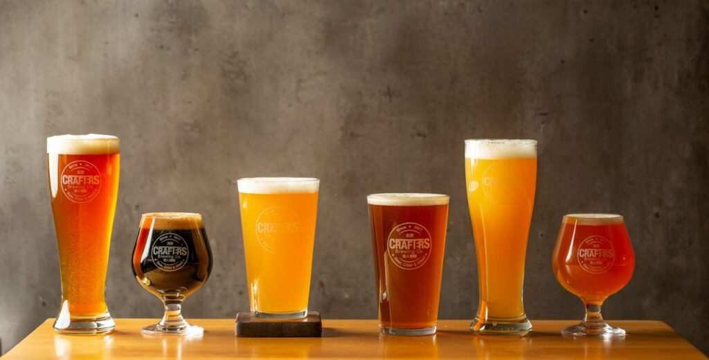 A variety of craft beer pints on a wooden bar, representing local breweries that ship nationwide