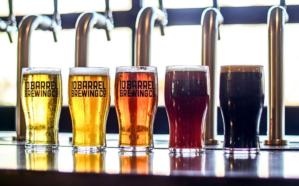 A small-town brewery taproom with rows of taps and barrels, highlighting a craft beer brand known nationwide