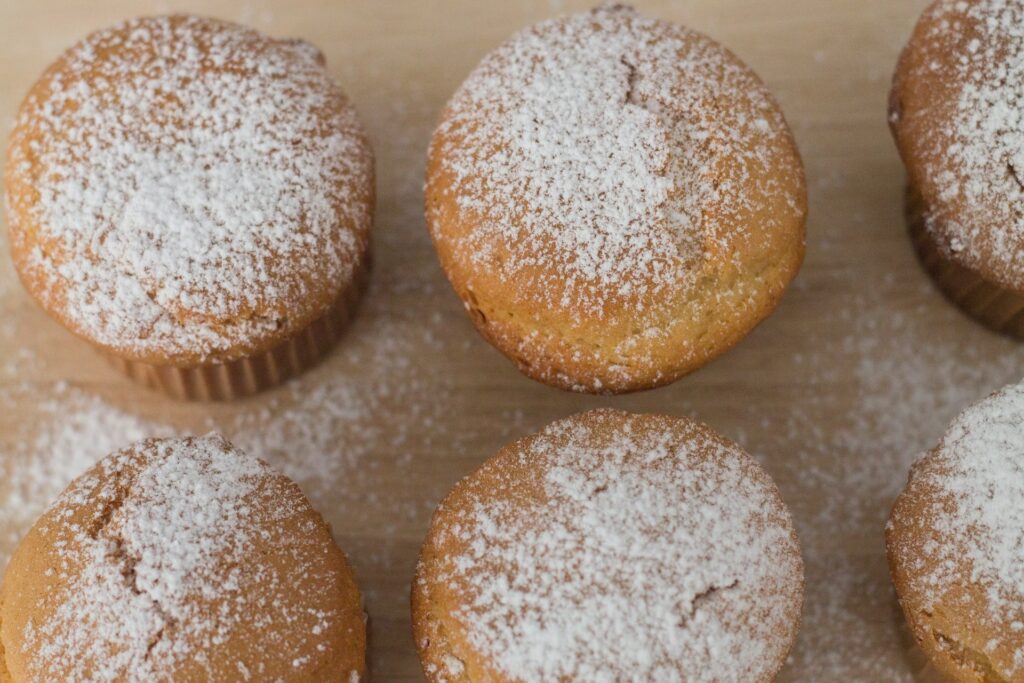 Powdered sugar-coated beignets served on a white plate with coffee