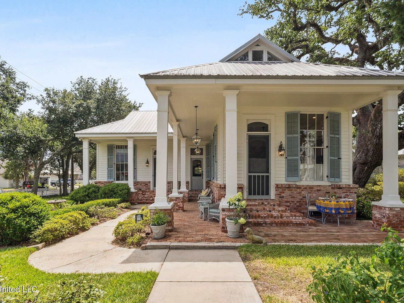 1900 Vernacular Cottage in Bay Saint Louis, Mississippi, Featuring a Wraparound Porch, Glass Accents, and a Guest Cottage