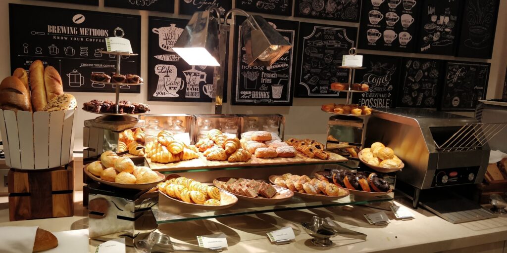 Assorted bakery display with croissants, muffins, cookies, and colorful pastries ready to grab