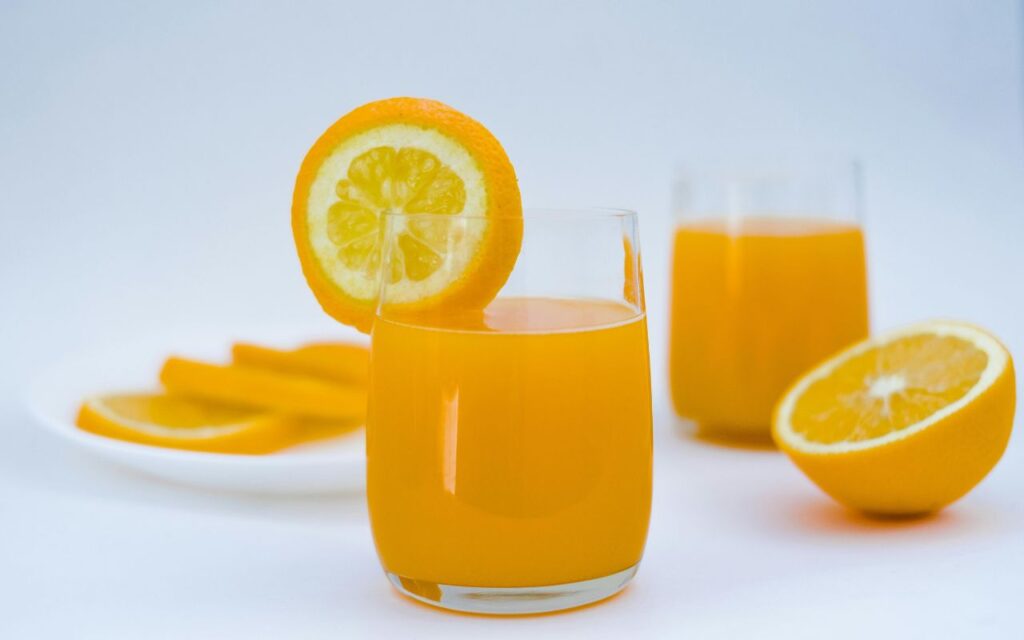Comparison of glass of hand-squeezed juice and a grocery store bottled juice on a countertop