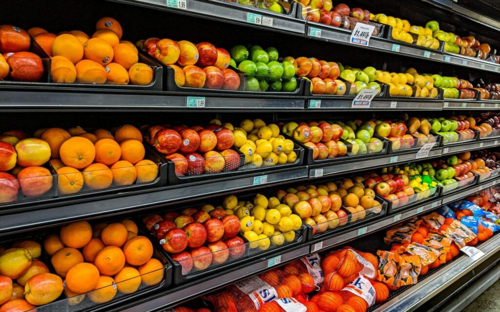 Wide view of industrial juicing equipment in a grocery store, processing large quantities of citrus fruit