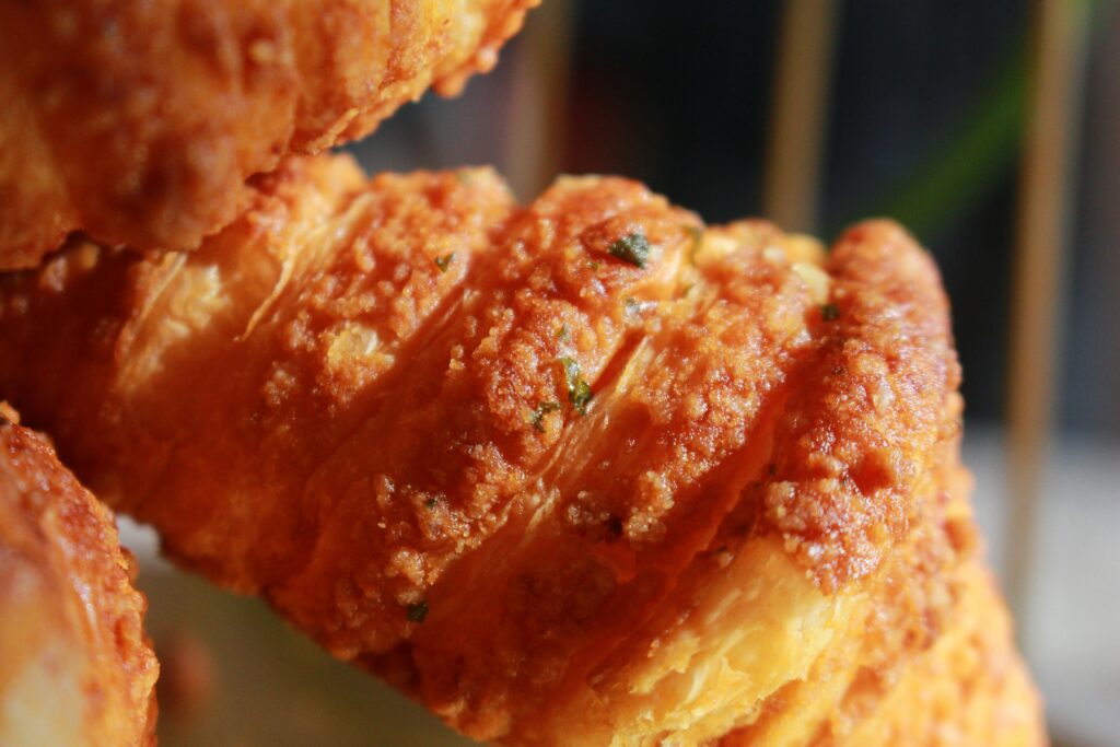 Fried soda pastry with crispy batter coating and sticky filling spilling slightly