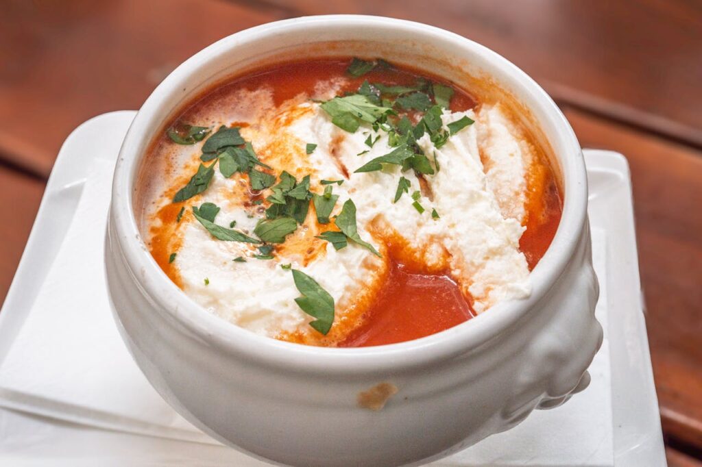 Grilled cheese sandwich cut in half served with a bowl of tomato soup for dipping