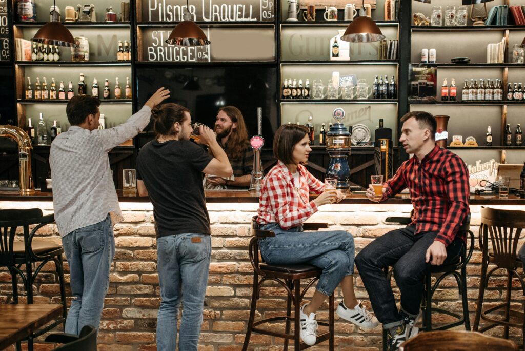 Busy taproom with patrons enjoying pints, showing a brewery that expanded its reach beyond the local community
