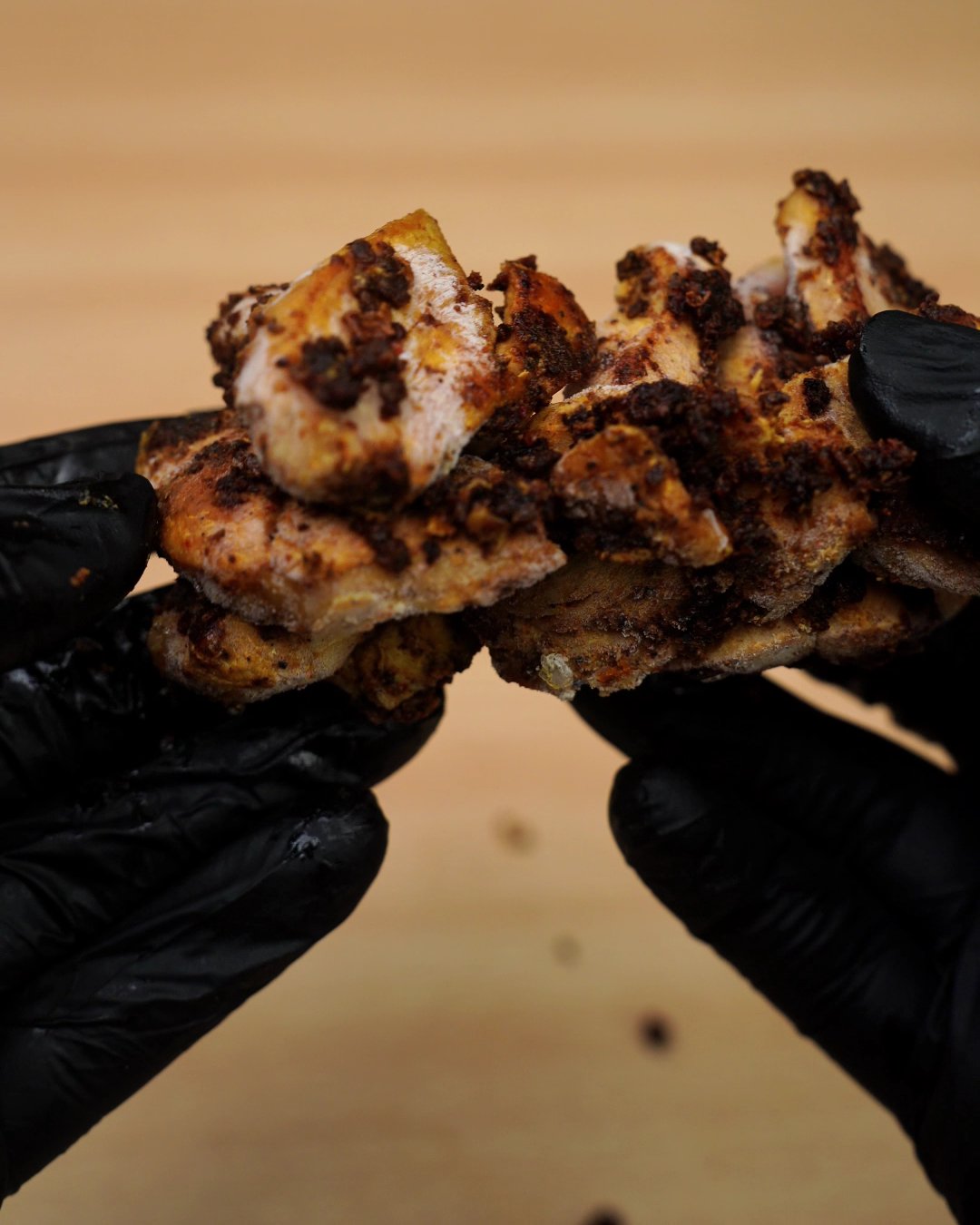 Frozen chunks of spice-crusted cooked chicken held in gloved hands