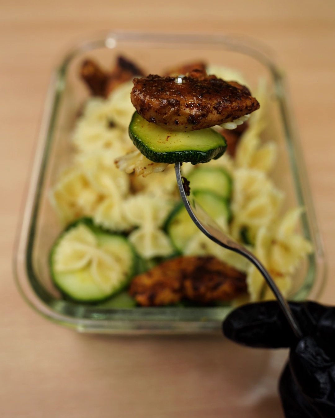 A forkful of spiced chicken and zucchini lifted from the reheated meal prep box