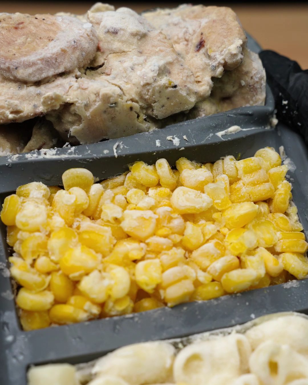 Frozen blocks of creamy chicken, sweet corn and macaroni in a gray silicone freezer mold