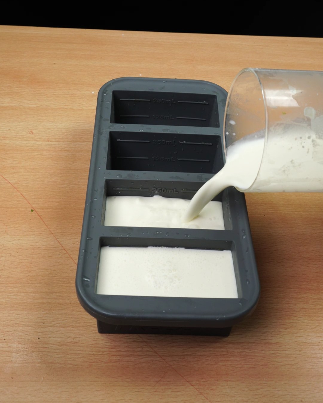 Pouring garlic Parmesan sauce into a silicone freezer mold