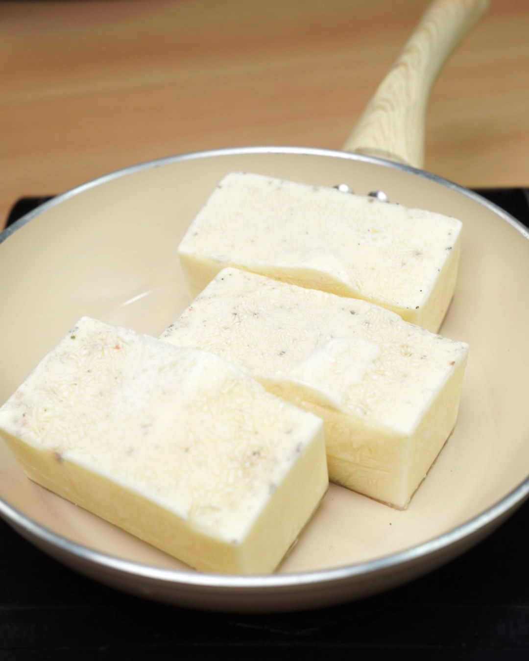 Frozen garlic Parmesan sauce blocks in a skillet