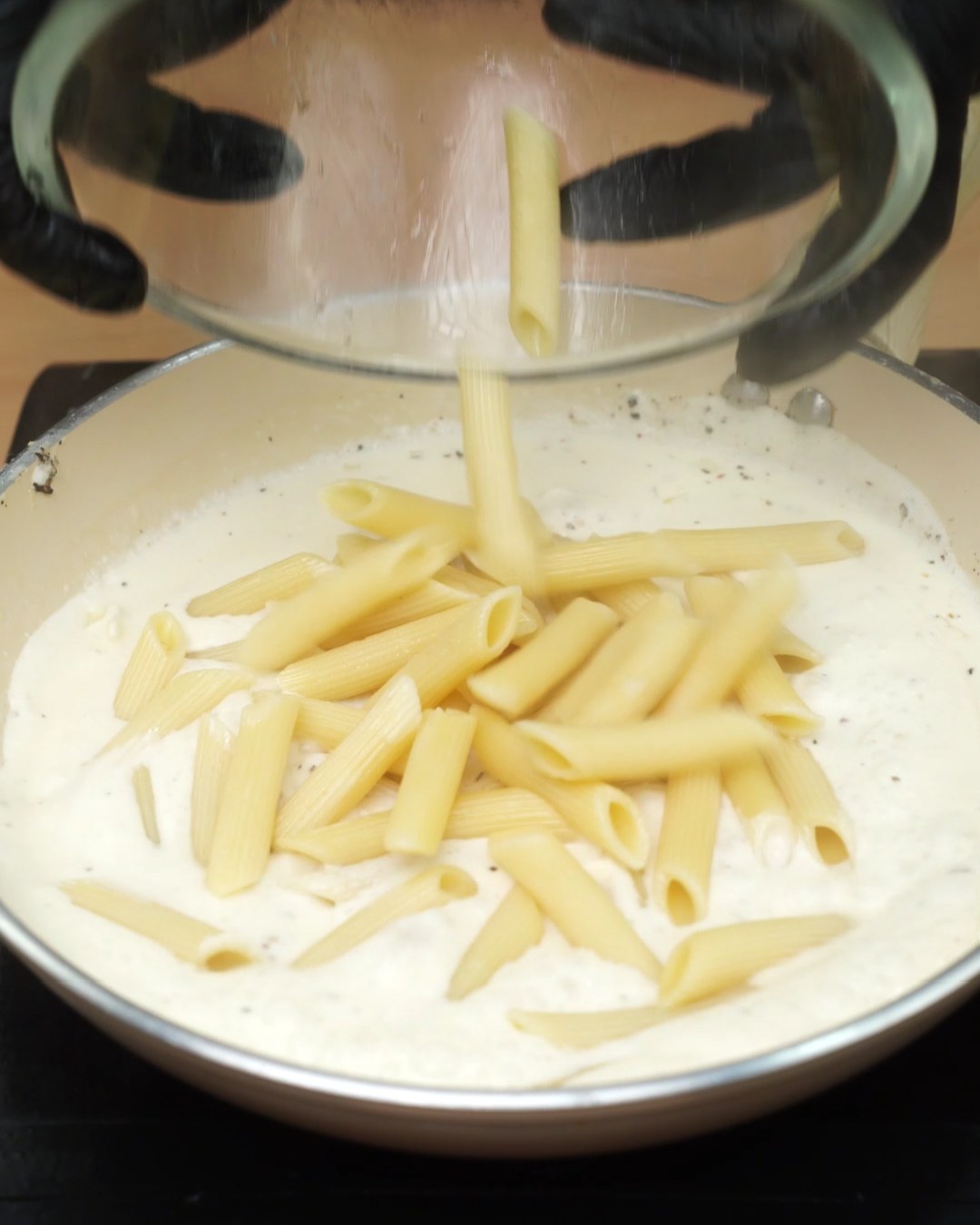 Cooked penne added to the garlic Parmesan sauce