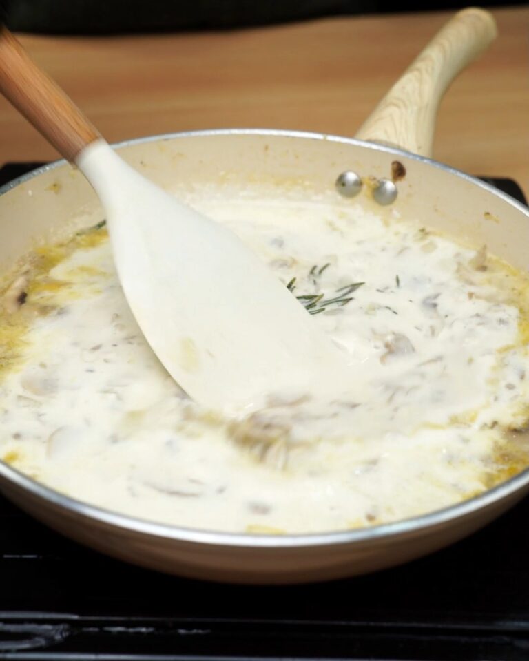 Creamy mushroom sauce being stirred with a spatula in a skillet