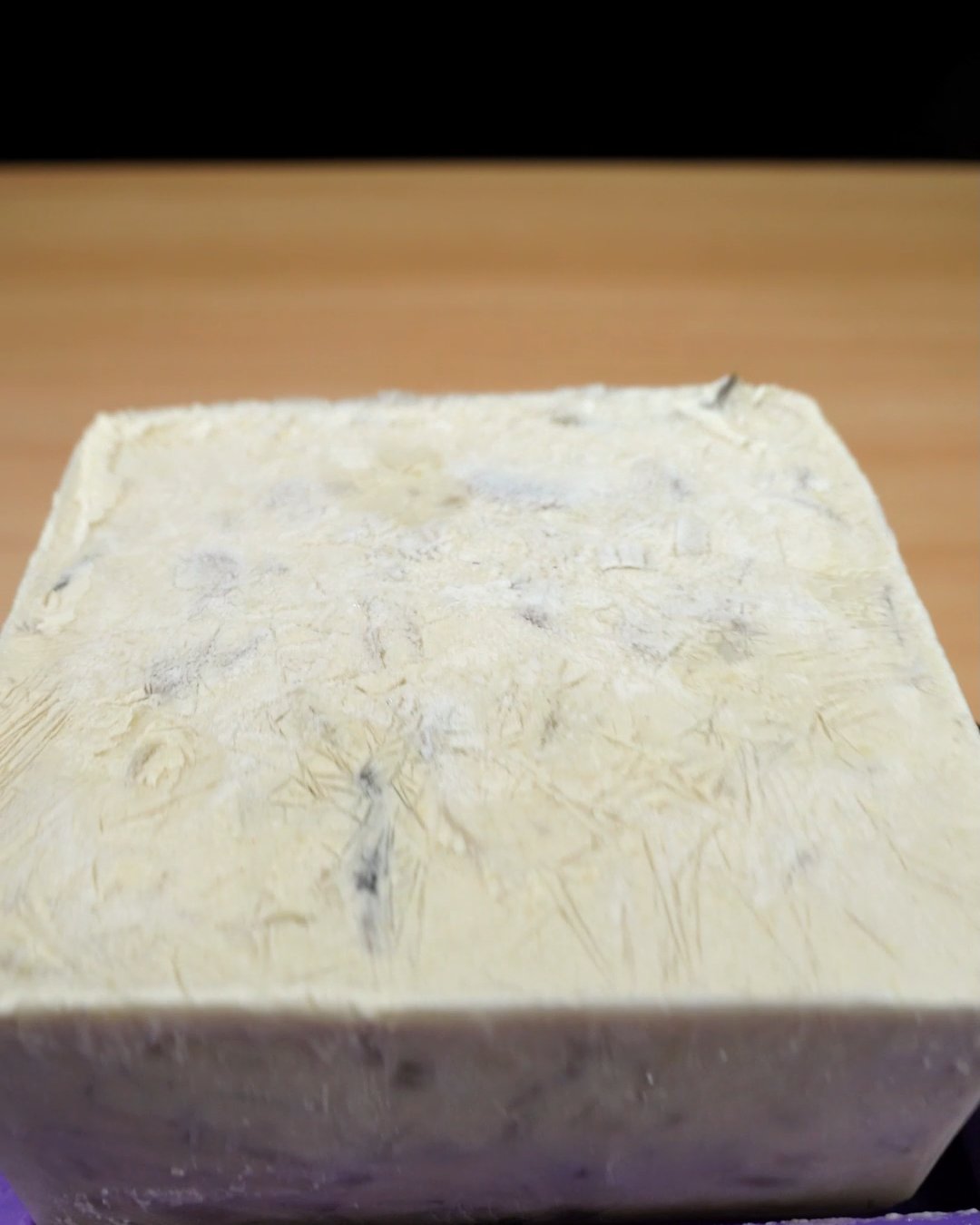 A frozen block of creamy mushroom sauce unmolded from a purple silicone freezer mold