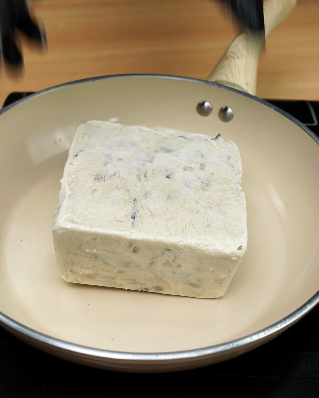 A frozen block of mushroom sauce placed in an empty skillet