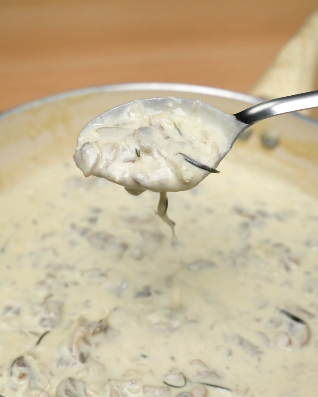 A spoonful of creamy mushroom sauce with sliced mushrooms and rosemary lifted from the skillet