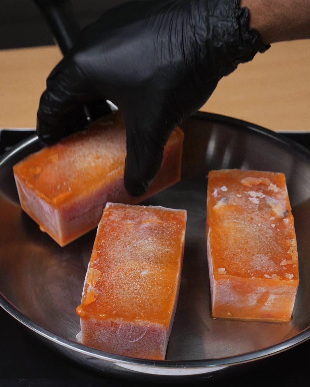 Frozen blocks of creamy tomato sauce placed in an empty skillet