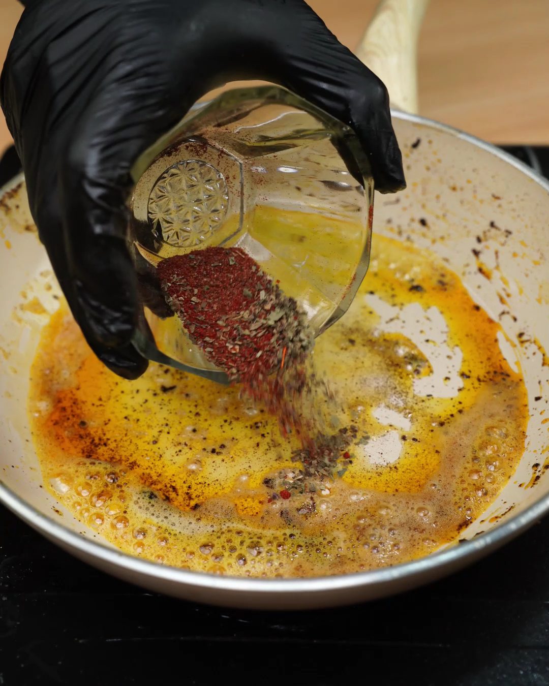 Paprika and dried herbs being added to melted butter in a skillet