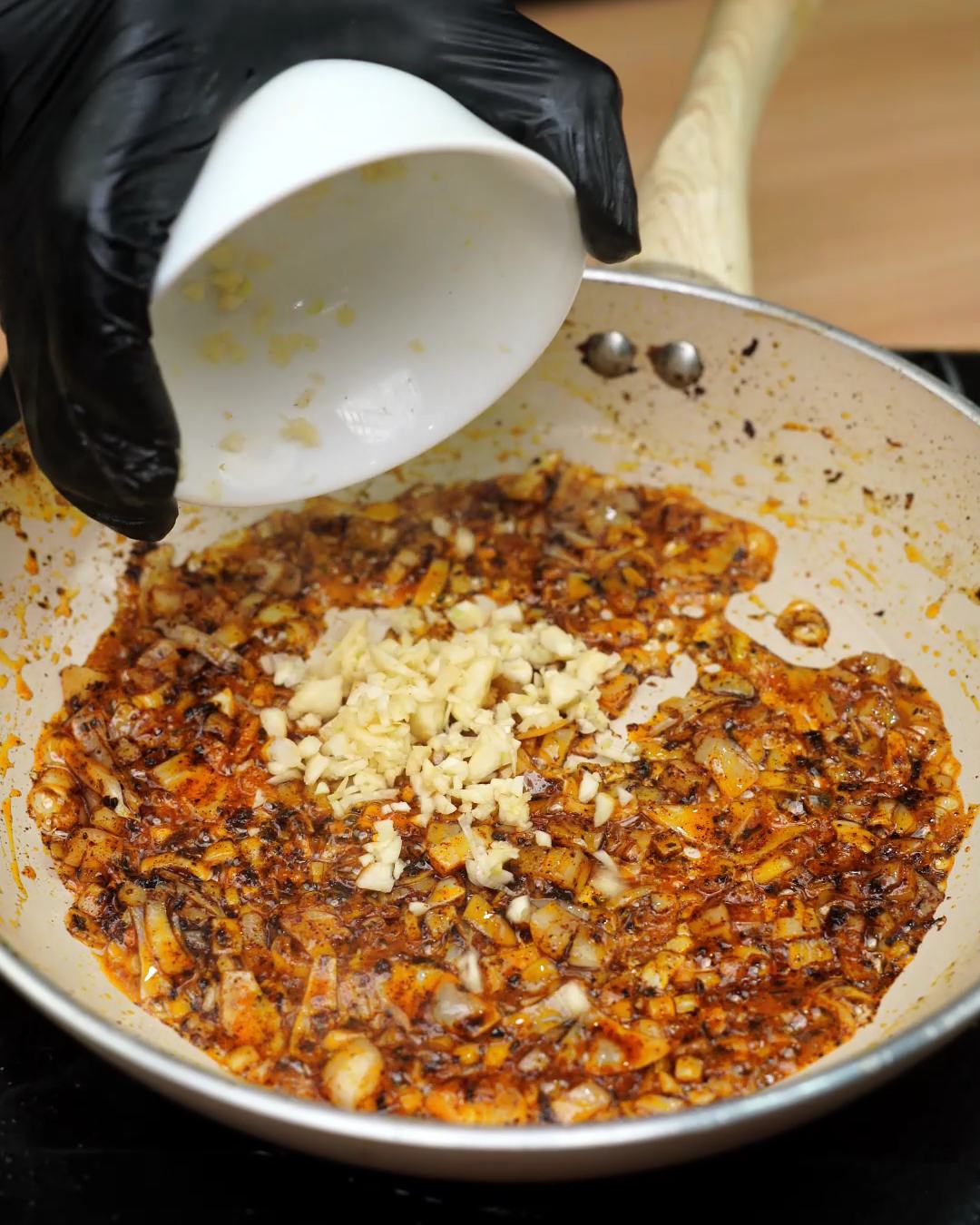 Minced garlic added on top of softened onion in a skillet