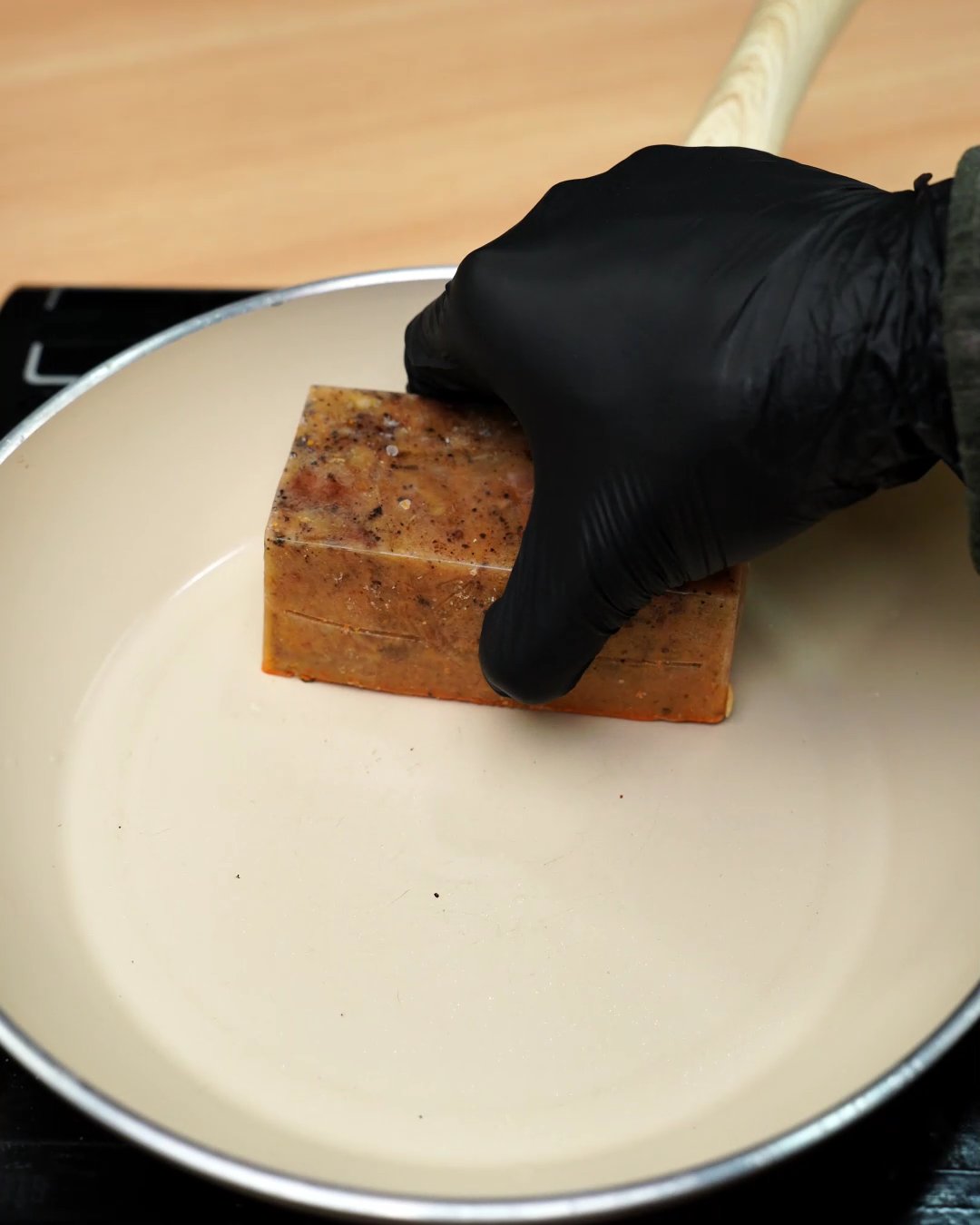 A frozen block of paprika chicken sauce being placed in an empty skillet