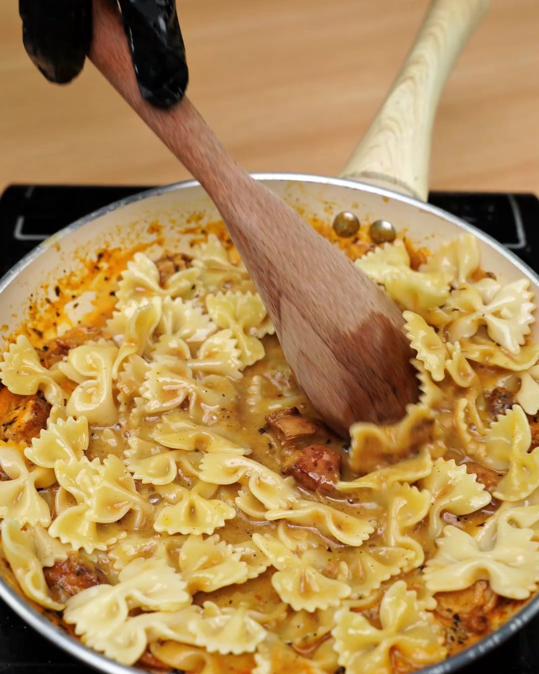 Bowtie pasta being stirred through the creamy paprika chicken sauce