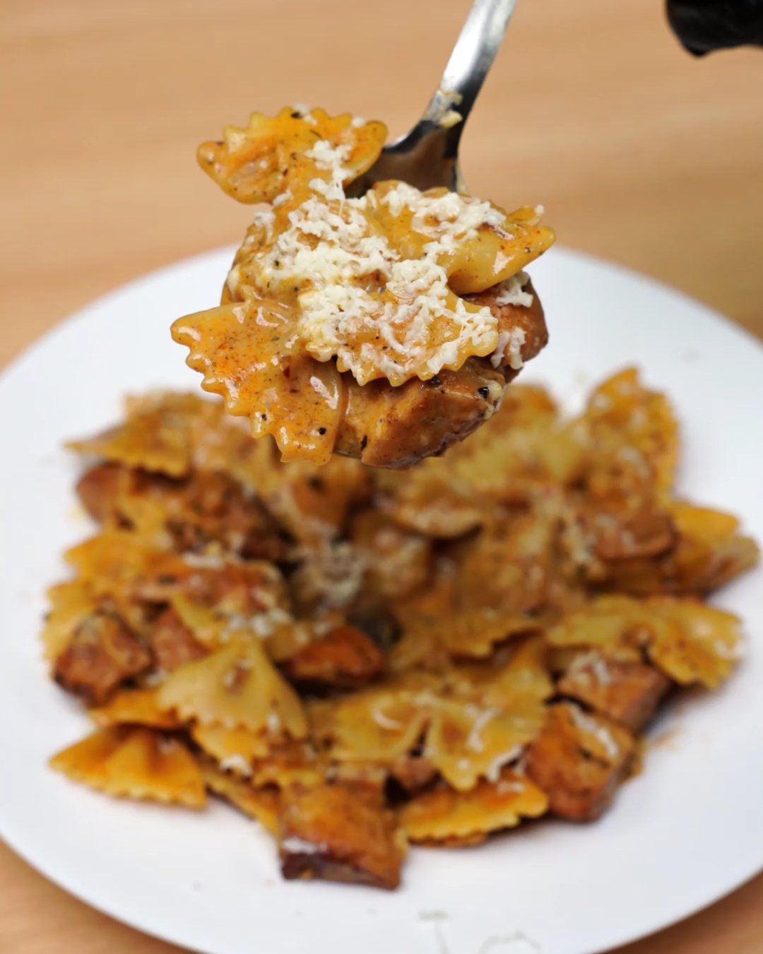 A spoonful of creamy paprika chicken bowtie pasta topped with grated Parmesan