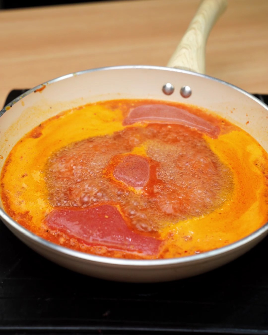Frozen tomato sauce blocks melting in the skillet