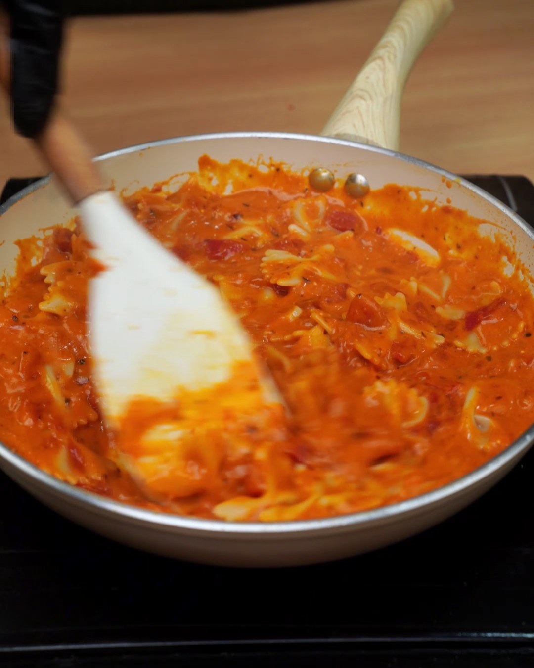 Tossing bowtie pasta through the sauce