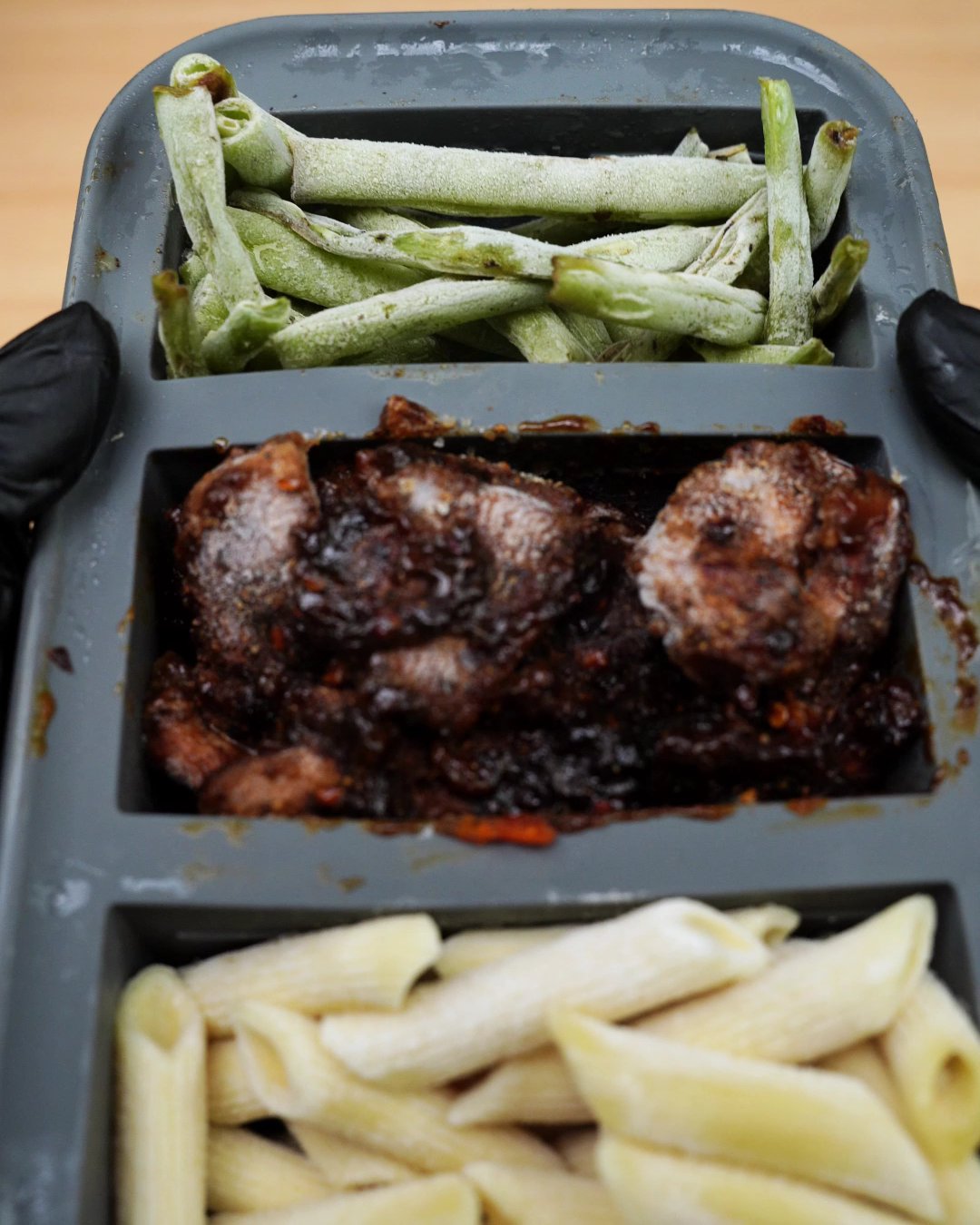 Silicone freezer tray holding frozen green beans and frozen glazed honey chicken portions