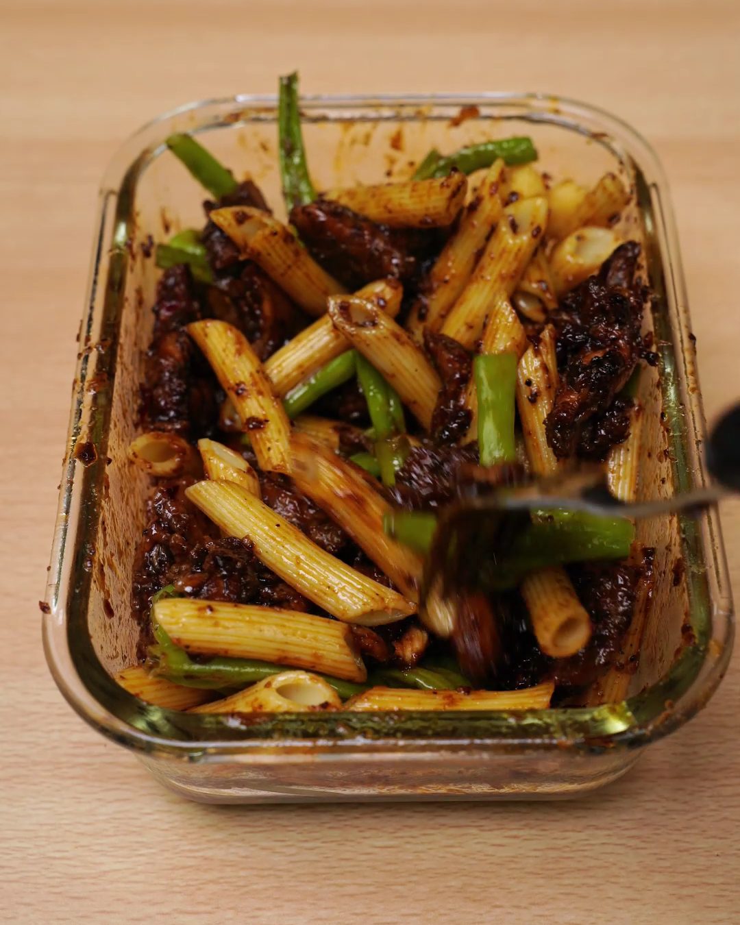 Honey chicken, penne and green beans tossed together in a sticky glaze in a glass container
