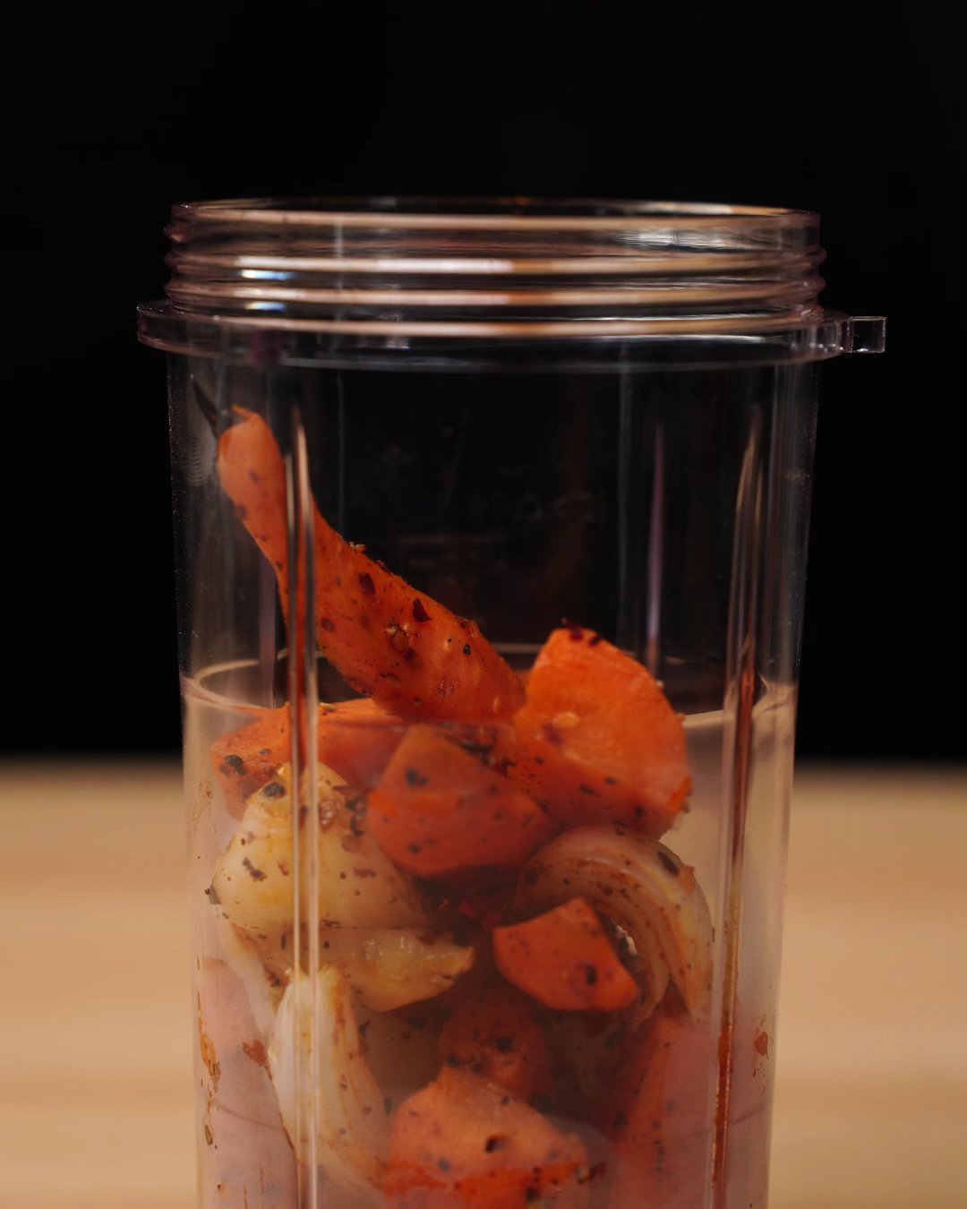 Blender cup filled with roasted carrots, garlic and onion