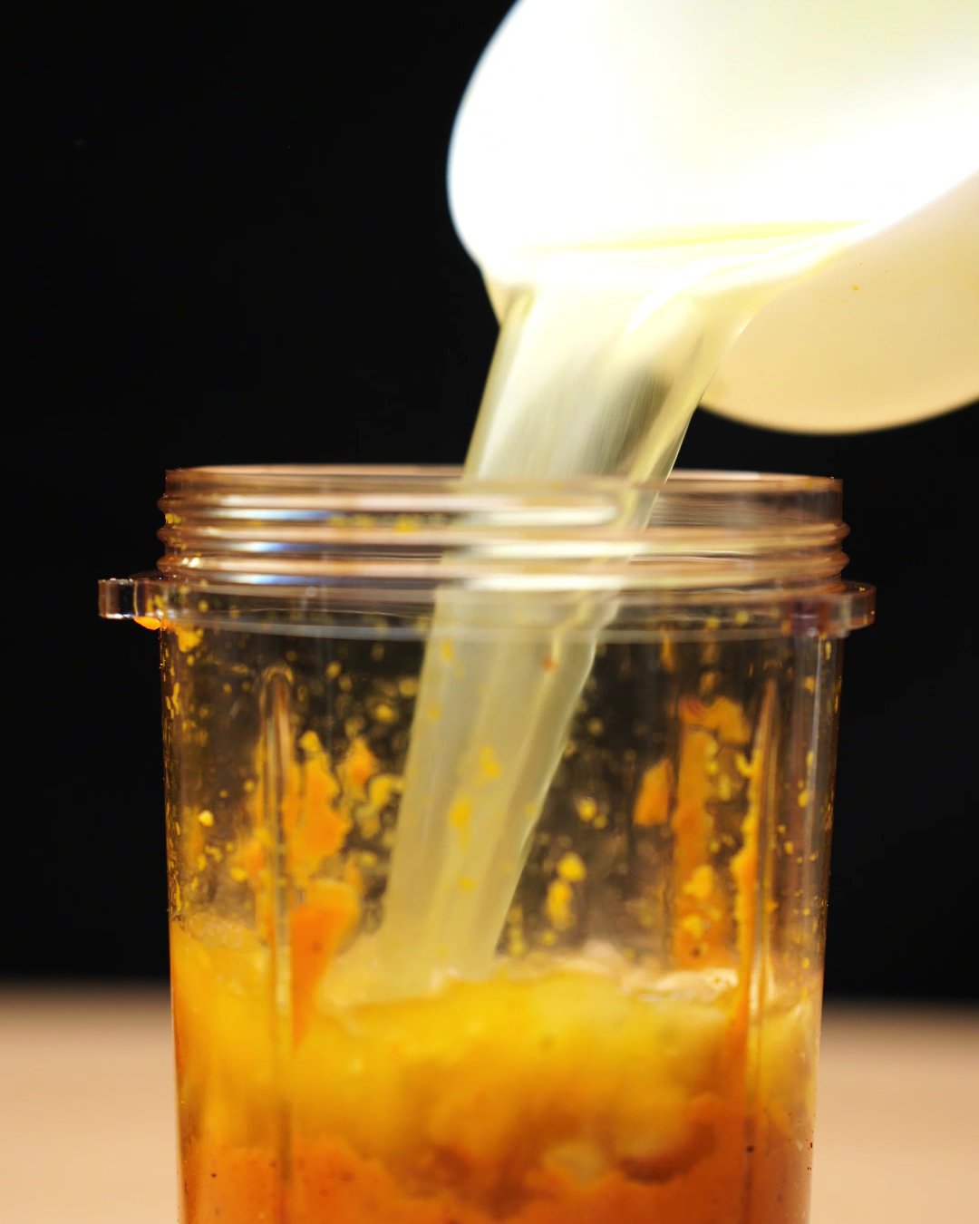 Broth being poured into a blender cup with carrot puree and chickpeas
