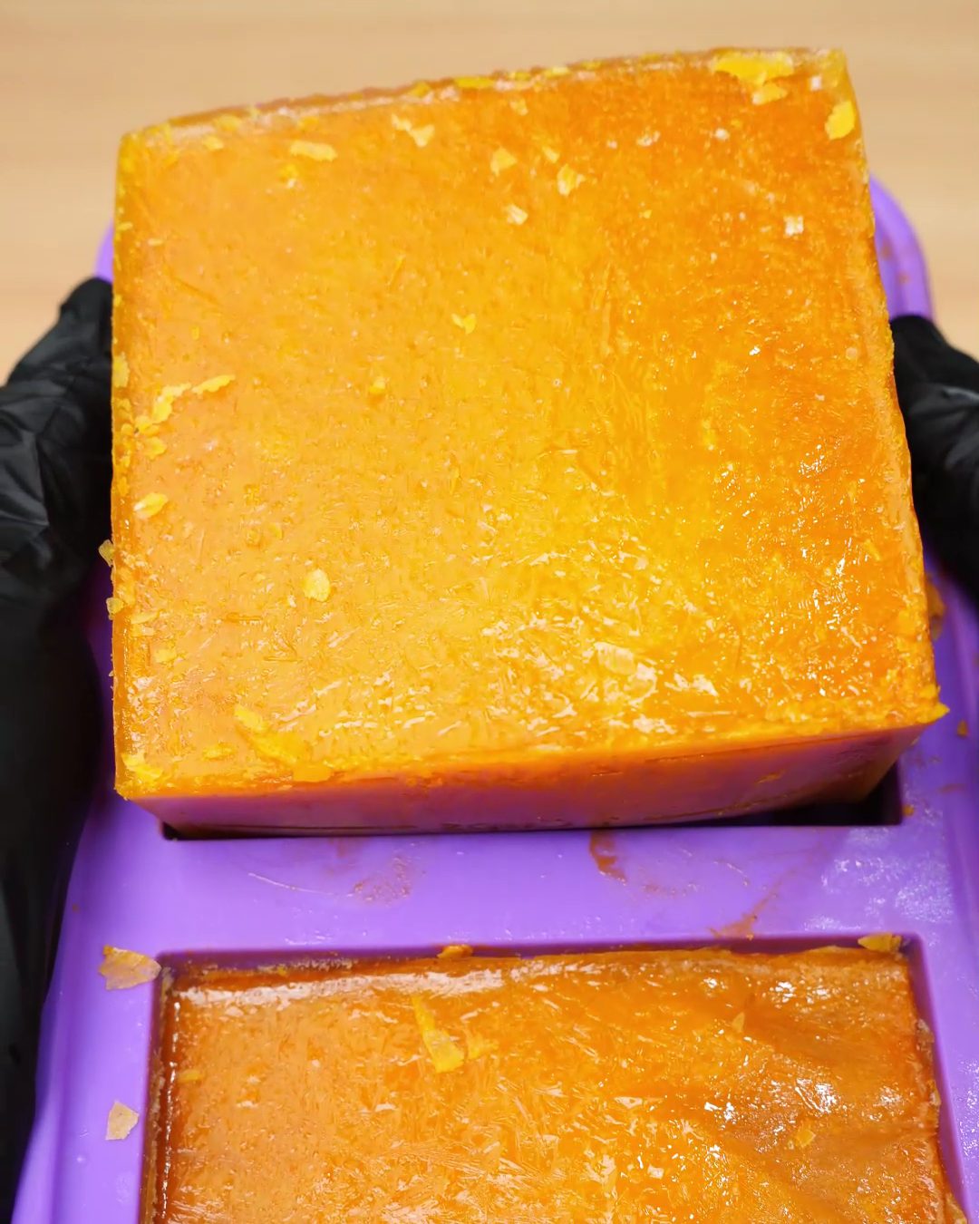 A frozen block of carrot soup being lifted out of a silicone mold