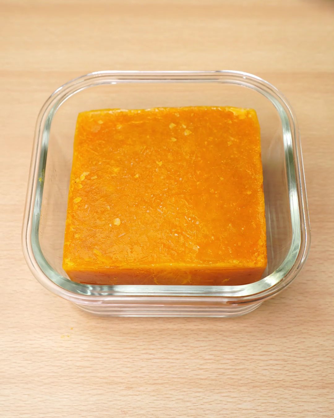 A frozen block of carrot soup in a square glass dish