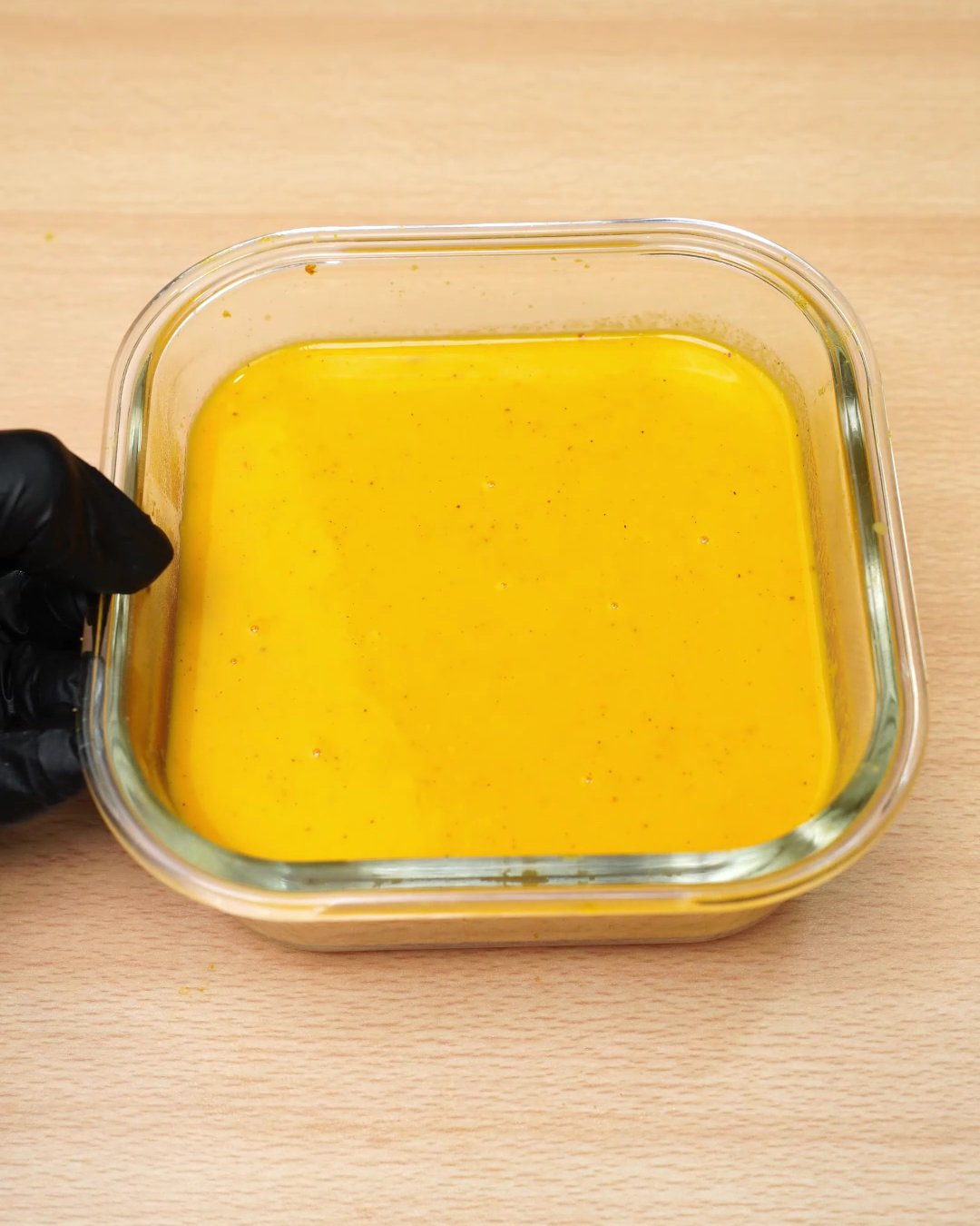 Reheated smooth carrot soup in a square glass dish