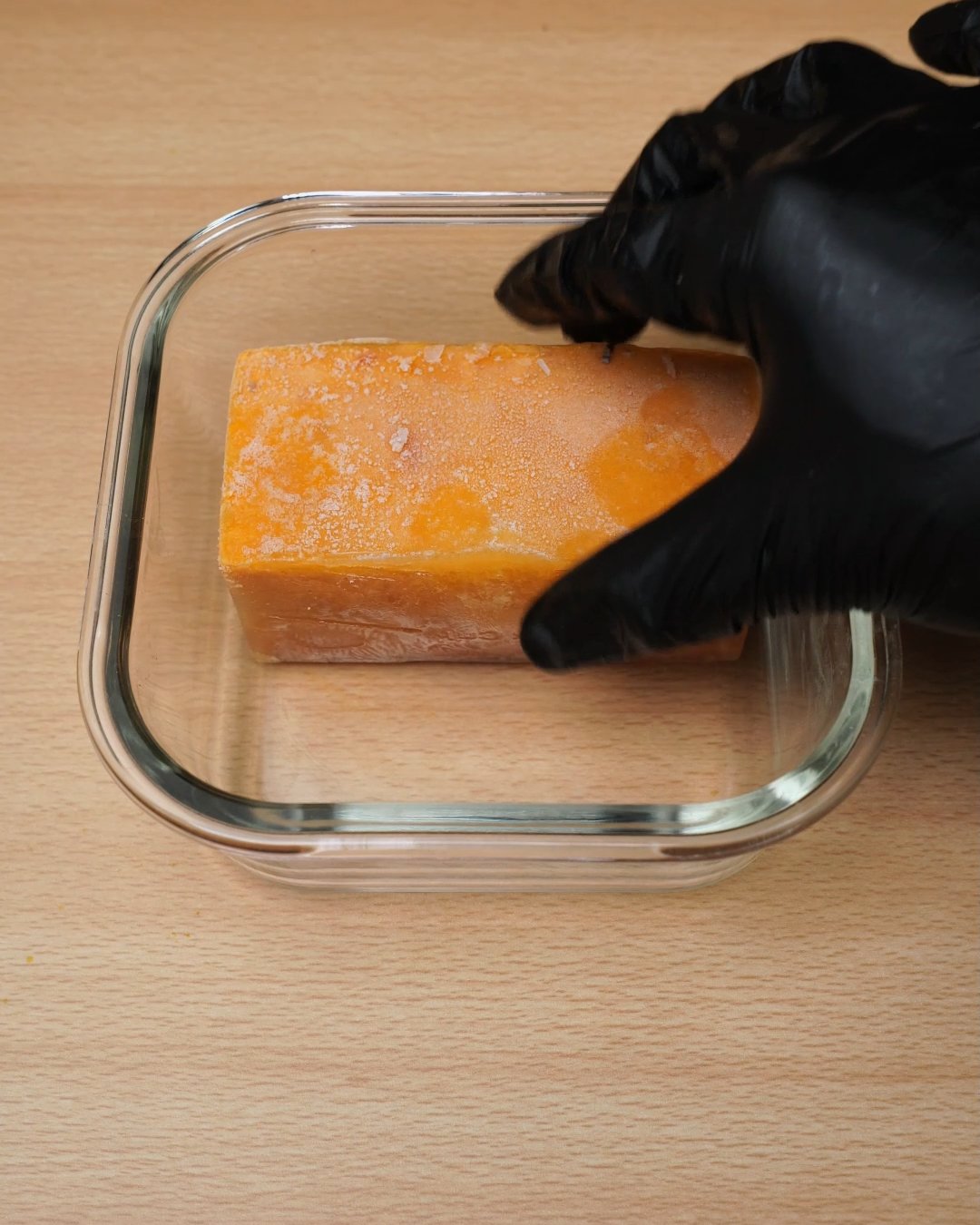 Frozen tomato cream sauce block being set into a square glass container