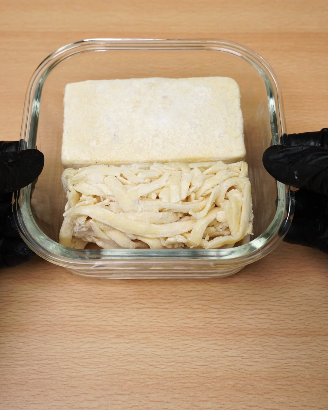 Glass container packed with a frozen Alfredo sauce block and frozen fettuccine