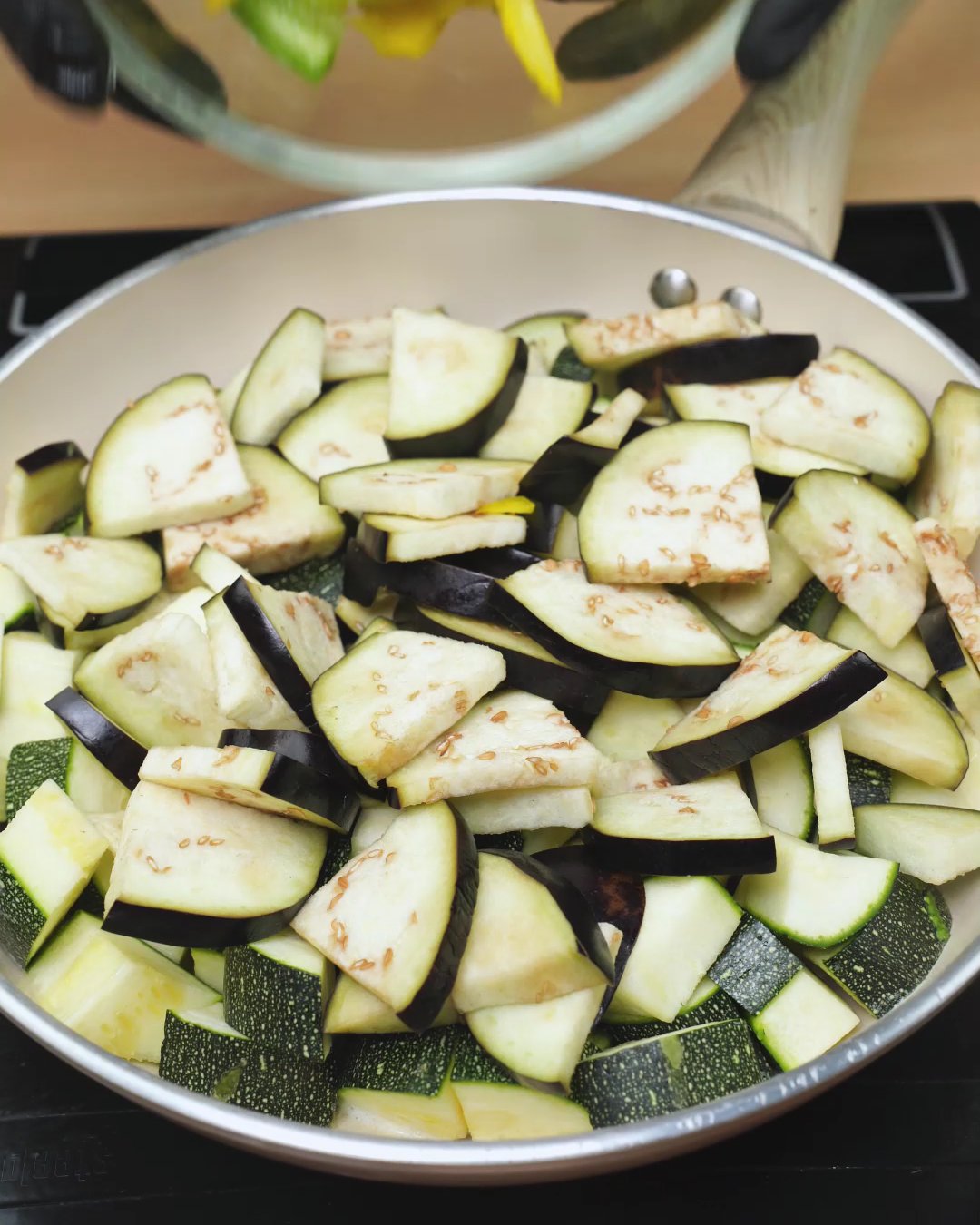 Sliced eggplant layered over diced zucchini in a skillet