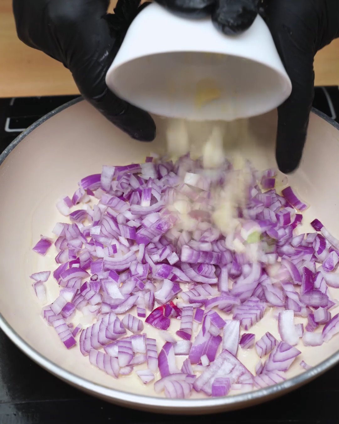 Finely chopped red onion cooking in a skillet