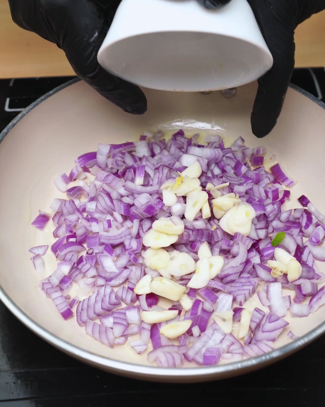 Chopped garlic added to red onion in a skillet