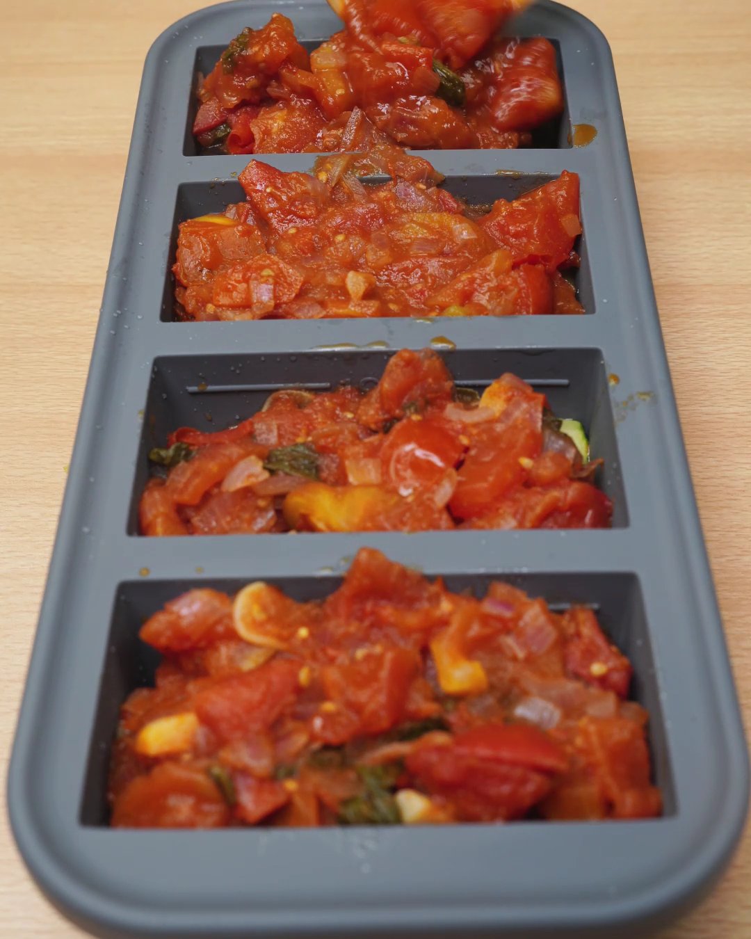 Silicone freezer mold filled with vegetables and tomato sauce, ready to freeze