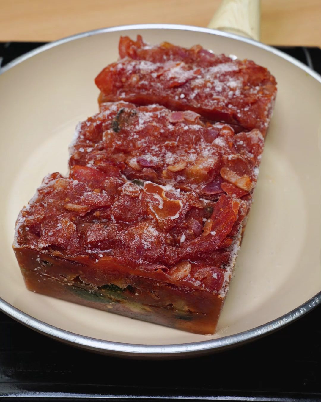 Frozen vegetable tomato sauce blocks in a skillet